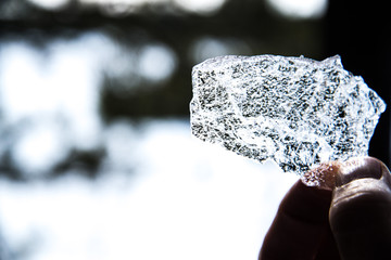 Big piece of shiny ice in hand, the ice is melting in the hand.