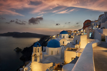 The famous three domes of Oia during beautiful sunset with pink sky on the Greek island of Santorini