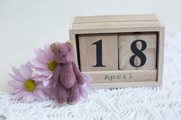 wooden calendar April 18 . toy bear and flowers