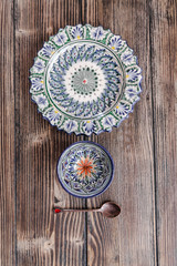 Fototapeta na wymiar Authentic middle east style plate, bowl and a bronze spoon on the wooden desk. Flat lay, top view. Vertical orientation.