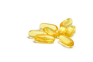 Close up of Pile gold color fish oil capsules isolated on white background view. Copy space. Salmon fish capsules view. For good health life from Omega 3 and Vitamin E. Supplementary food background.