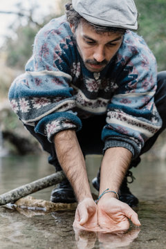 Young man scooping water near Cova Simanya, Barcelona, Spain.