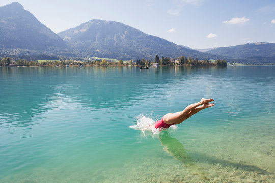 Austria, Alps, Salzburg, Salzkammergut, Salzburger Land, Wolfgangsee, Woman Jumping Into Lake