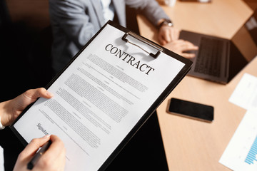 Close-up photo of business woman and man signing a contract in moden office.
