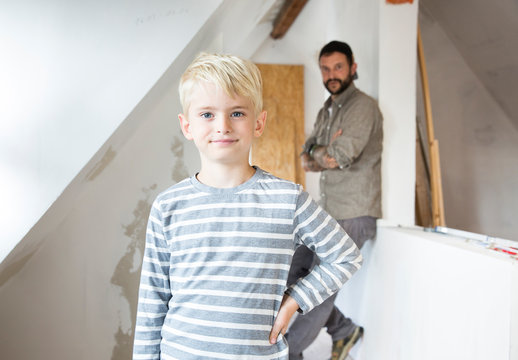 Portrait of confident boy working with father on loft conversion