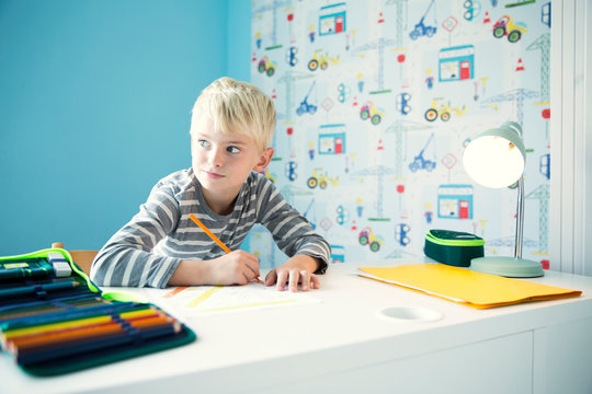 Boy doing homework at desk in children's room