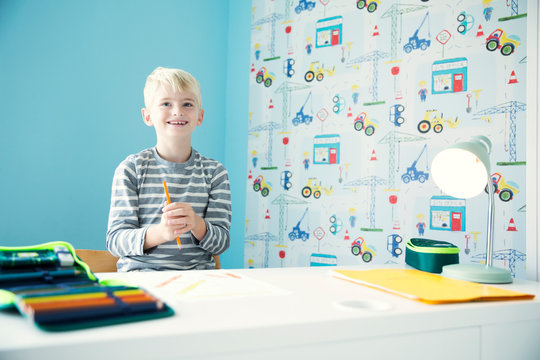 Smiling boy doing homework at desk in children's room