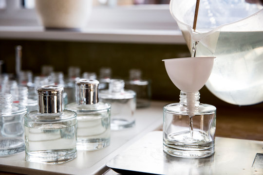 Close up of person pouring liquid for scent diffuser into glass bottle.