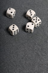 White dice with black markings. Lie on a surface covered with a coarse gray cloth