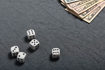 White dice with black markings. They lie on a surface covered with a coarse gray cloth. Nearby are...