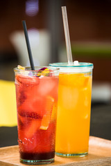 Fresh lemonade with straws with fresh strawberry and orange on a bar table.