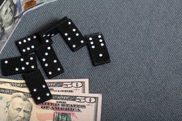 Domino knuckles on a surface covered with a coarse gray cloth. Nearby are a few dollar bills of...