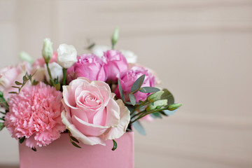 Stylish wedding bouquet bride of pink roses, white carnation and green flowers and greens with ribbons lying on pastel table