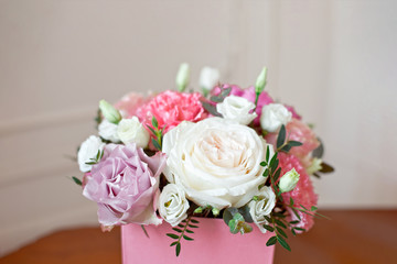 Stylish wedding bouquet bride of pink roses, white carnation and green flowers and greens with ribbons lying on pastel table