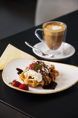 Cafe tabletop with sweet pastries, strawberries and cream and coffee latte. 