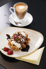 Cafe tabletop with sweet pastries, strawberries and cream and coffee latte. 