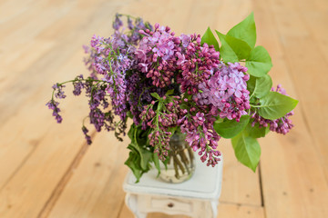 Beautiful lilac flowers in vase, on wooden table