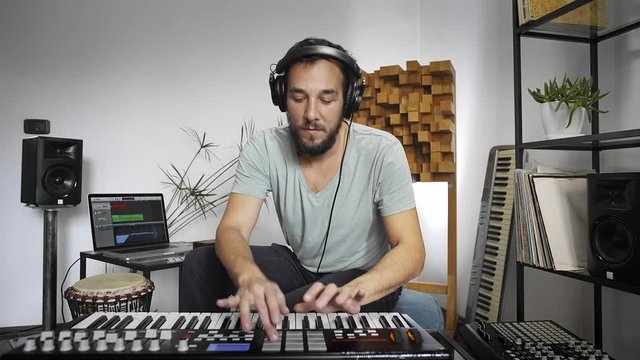 Musician playing midi keyboard in home music studio.