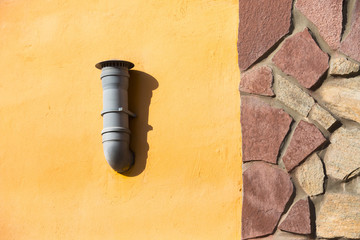 Plastic vent pipe on the orange wall. Air ventilation pipe mounted on the exterior wall