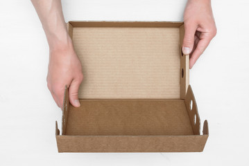 A parcel cardboard box in a delivery man hands on a white wooden table background. Delivery service concept.