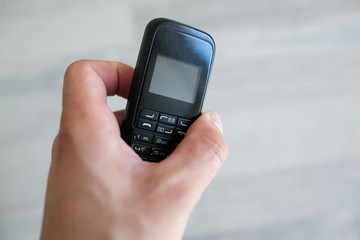 Close-up of man hand holding old black mobile phone