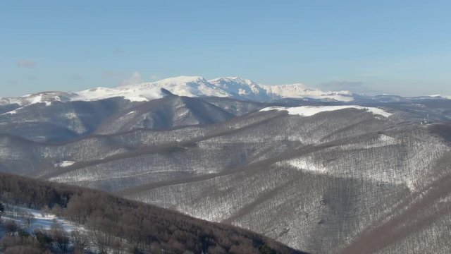 Panoramic flight of the drone over the tops of mountains in Bulgaria, covered with growth, trees and snow. Beautiful landscape view on top of mountain in the morning in Bolgatia, Top view of tree fore