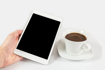 Fototapeta na wymiar Digital tablet in one hand, on a white background next to coffee mug full of coffee, isolated
