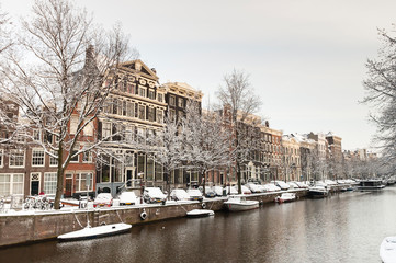 Snow covered Amsterdam canal in cold winter. Amsterdam is the capital of the Netherlands.