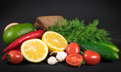 Fototapeta na wymiar eggs, greens, black bread, cucumbers, garlic, avocado, pepper, tomatoes, on a black background