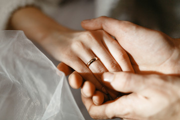 Image of hands of a man and a woman with wedding rings on a white background