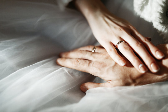 Image of hands of a man and a woman with wedding rings on a white background