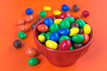 Fototapeta na wymiar colored bowl full of colorful chocolates on colored background