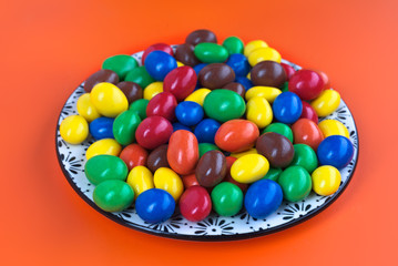 Fototapeta na wymiar dish full of colorful chocolates on colored background