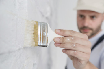 Painting a white brick wall with a paint brush - obrazy, fototapety, plakaty