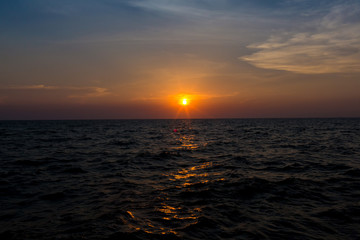 Bright sunset with large yellow sun under the sea surface. sunrise in the sea. Beautiful sunset above the sea. Tropical sunset on the beach.