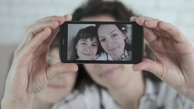 Family makes selfie. Cute mother with her daughter are photographed on a smartphone.