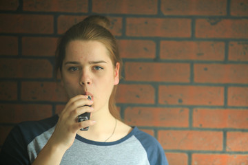 Vape teenager with  problem skin. Portrait of young cute girl smoking an electronic cigarette in...