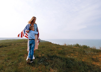 Naklejka premium happy mother and son turned around american flag
