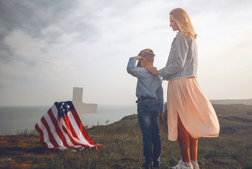 mother with son in the cemetery near the grave of the father of the American soldier who died in...