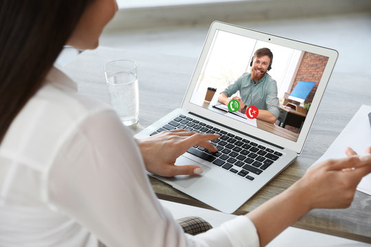 Woman having video chat with colleague at table in office, closeup