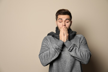 Handsome young man coughing against color background. Space for text