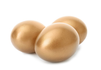 Three shiny golden eggs on white background