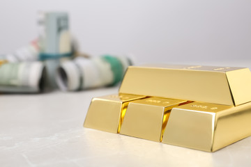 Shiny gold bars and dollar rolls on table, closeup. Space for text