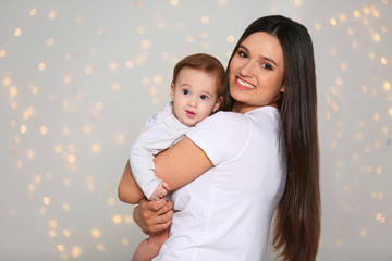 Portrait of young mother and her adorable baby against defocused lights