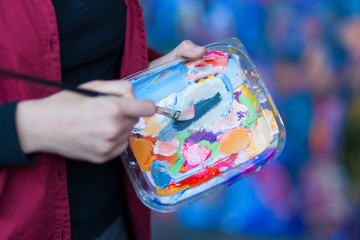 detail of a woman artist holding palette for mixing colors