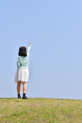 青空でガッツポーズをきめる女の子（後姿）