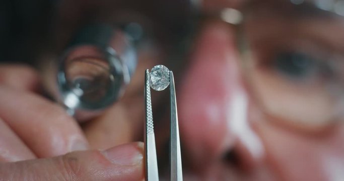 Slow motion macro close up of experienced goldsmith controlling a quality of diamond stone, selected for making jewels in workshop.Shot in 8K. Concept of jewelry,luxury,goldsmith, diamonds, brilliance