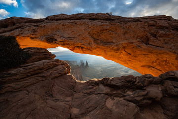 Mesa arch at sunrise from Canyonlands National Park near Moab Utah USA. The orange rim glow on the underside arch wall is courtesy of the rising sun.