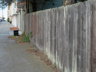 Unpainted wooden fence on a quiet neighborhood street in the daytime