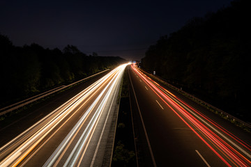 Fototapeta na wymiar Langzeitbelichtung auf der Autobahn. Nachtlichter, Stadtlichter, Geschwindigkeit, Transport, Traffic, Autos in Bewegung, Fahrbahn, Road